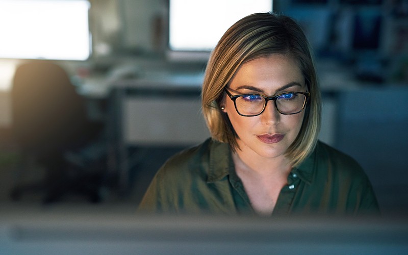 Businesswoman in glasses reviews security assessment on computer